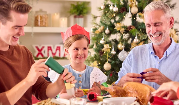 Flergenerationsfamilj Firar Jul Hemma Pulling Crackers Innan Äter Mat Tillsammans — Stockfoto
