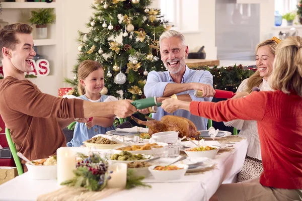 Mehrgenerationenfamilie Feiert Weihnachten Hause Und Zieht Cracker Vor Dem Gemeinsamen — Stockfoto