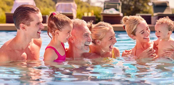 水泳プールでリラックスした夏休みに赤ちゃん男の子と一緒に笑顔世代の家族 — ストック写真