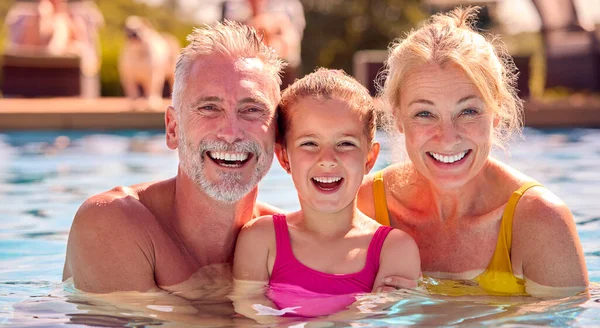祖父母の肖像プールで家族の夏休みに泳ぐ孫娘を教える — ストック写真