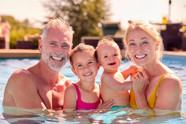 プールで家族の夏休みに孫と楽しむ祖父母の肖像画 — ストック写真