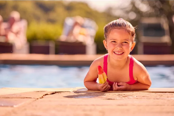 夏休みにプールの端でアイスロリーを食べる女の子と家族の肖像 — ストック写真