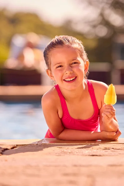 家庭在暑假与女孩一起吃冰棍在游泳池边的肖像 — 图库照片