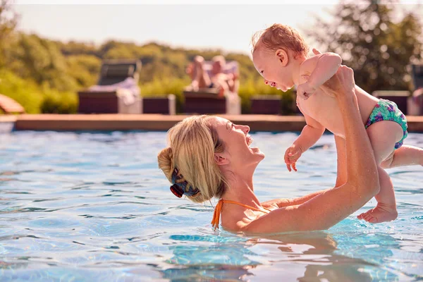 妈妈带着小儿子在暑假里在游泳池里玩耍 — 图库照片