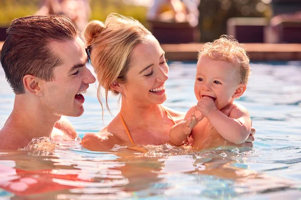 水泳プールで遊ぶ夏休みに赤ちゃんの息子と一緒に笑顔の家族 — ストック写真