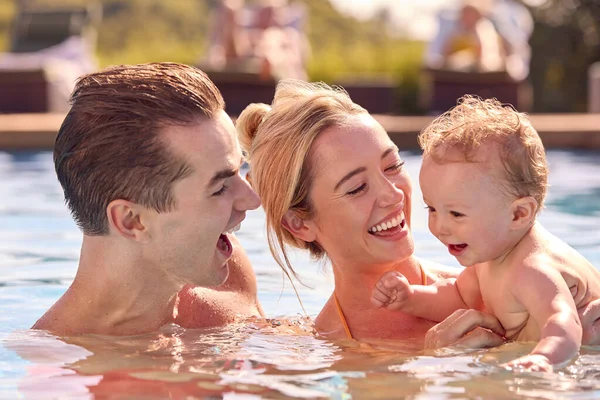 水泳プールで遊ぶ夏休みに赤ちゃんの息子と一緒に笑顔の家族 — ストック写真
