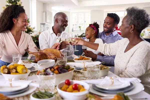 Familia Multi Generación Celebrando Navidad Casa Comiendo Comida Haciendo Tostadas — Foto de Stock