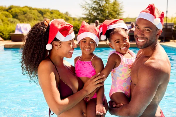 サンタの帽子をかぶってスイミングプールでのクリスマス休暇中の家族の肖像 — ストック写真
