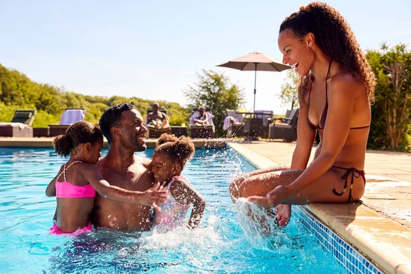 お父さんがプールで開催されている2人の女の子と夏休みに家族お母さんをスプラッシュ — ストック写真