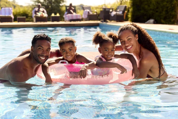 ポートレート家族で夏休みに2人の女の子が水泳プールに浮かんでいるインフレータブルリング — ストック写真