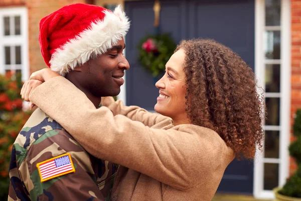 身穿制服 头戴圣诞老人帽的美国士兵在圣诞假期回家拥抱女人 — 图库照片