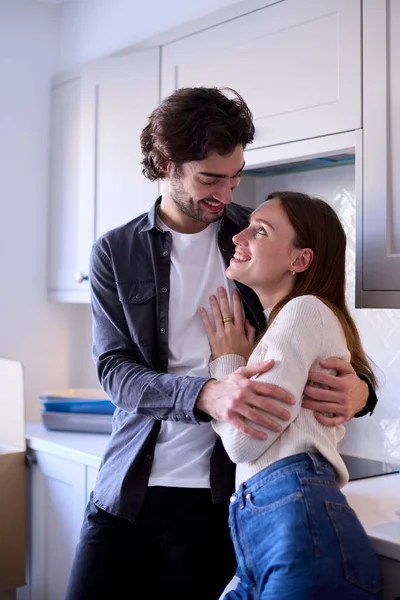 若いカップルが一緒にキッチンで箱をアンパックして新しい家の抱擁に移動します — ストック写真