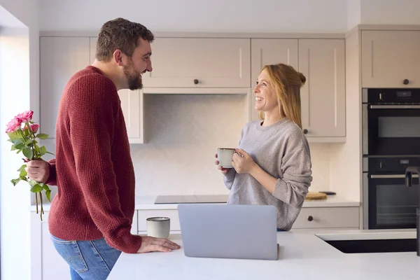 Couple At Home Looking At Laptop On Counter In Kitchen Together