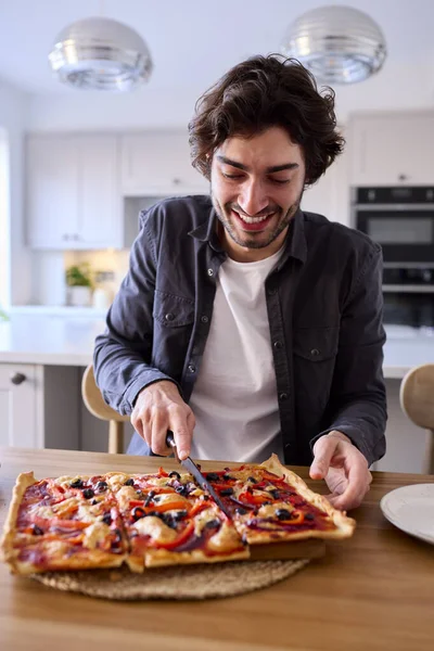 Man Keuken Thuis Snijden Eten Van Zelfgemaakte Pizza Zitten Teller — Stockfoto