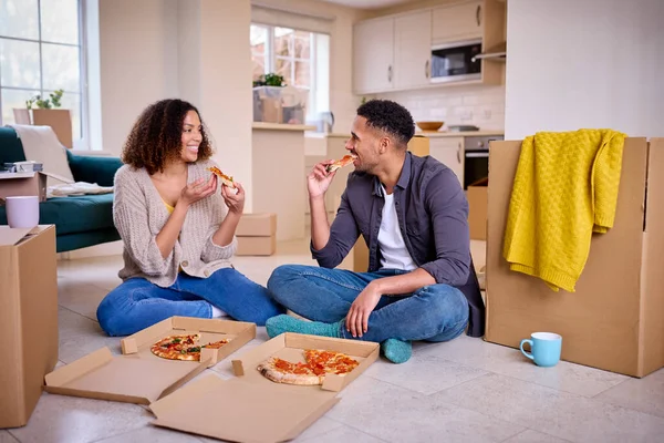 一对兴奋的夫妇搬进新家庆祝坐在地板上吃外卖比萨 — 图库照片