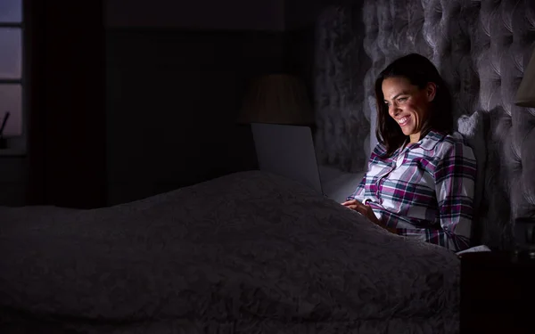 Усміхнена Жінка Вдома Сидить Ліжку Використовуючи Ноутбук Вночі — стокове фото