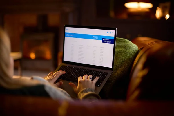 女人躺在客厅里躺在沙发上 火冒三丈地看着笔记本电脑上的网上银行账户 — 图库照片