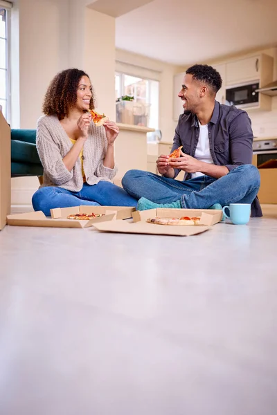 一对兴奋的夫妇搬进新家庆祝坐在地板上吃外卖比萨 — 图库照片