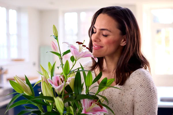 笑顔の女性で家の匂いとガラス花瓶の花の花束を手配 — ストック写真