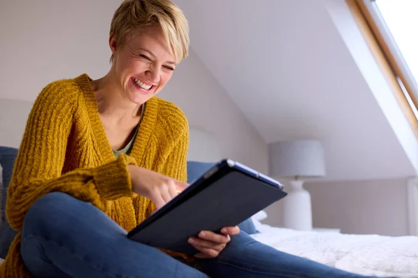 Młoda Kobieta Siedzi Łóżku Domu Śmiejąc Się Patrząc Cyfrowy Tablet — Zdjęcie stockowe