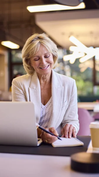 Uśmiechnięta Dojrzała Bizneswoman Pracująca Laptopie Biurze Robiąc Notatki — Zdjęcie stockowe