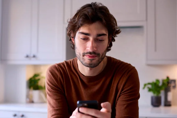 Ung Man Avslappnande Hemma Köket Kontrollera Meddelanden Sociala Medier Mobiltelefon — Stockfoto