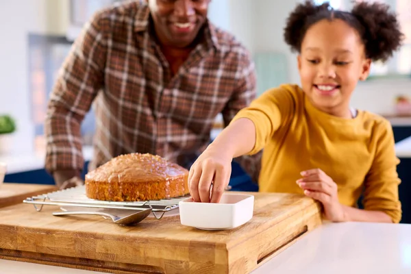 スプリンクルでケーキを飾るキッチンで父と娘と一緒に家で焼く家族のショット — ストック写真