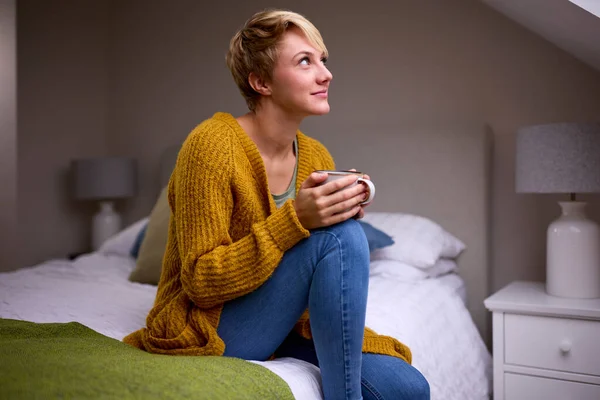 Junge Frau Mit Heißgetränk Sitzt Auf Bett Hause — Stockfoto