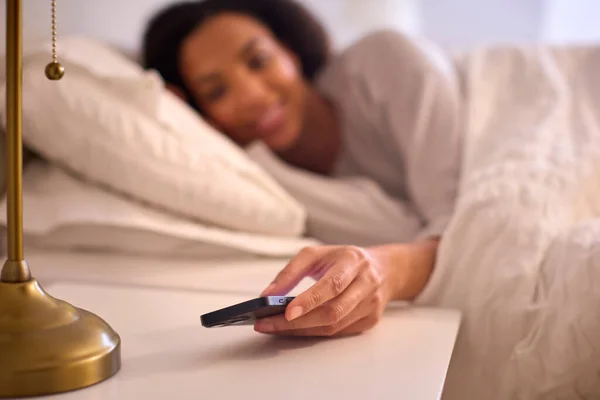 妇女在家睡觉时关掉手机上的闹钟 — 图库照片
