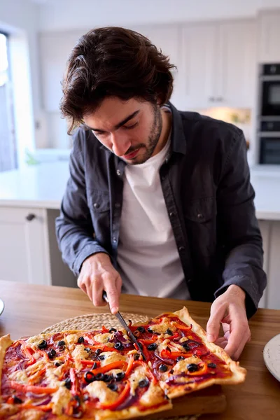 Άνθρωπος Στην Κουζίνα Στο Σπίτι Κοπής Και Τρώει Σπιτική Πίτσα — Φωτογραφία Αρχείου