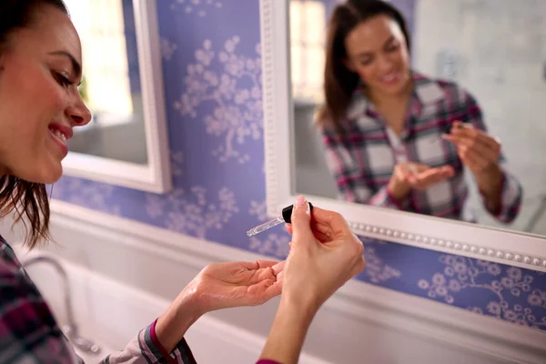 Evde Pijama Giyen Aynaya Bakan Saç Yağı Kullanan Bir Kadın — Stok fotoğraf