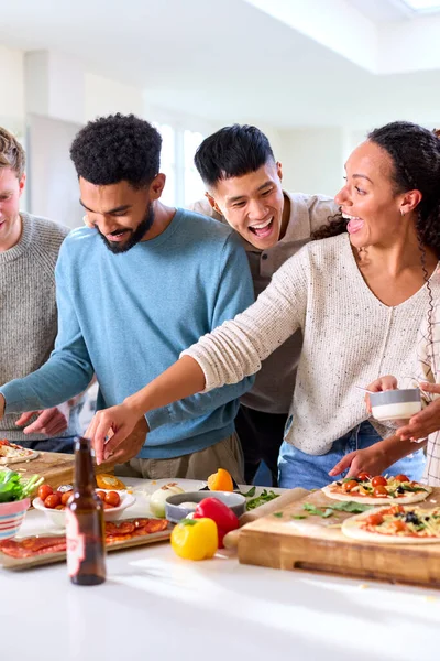 Gruppo Amici Casa Cucina Che Aggiungono Condimenti Alle Pizze Fatte — Foto Stock