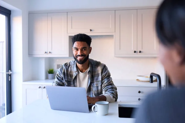 Couple At Home Working On Laptop On Counter In Kitchen