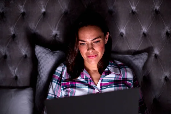 Mujer Sonriente Casa Sentada Cama Usando Ordenador Portátil Por Noche — Foto de Stock