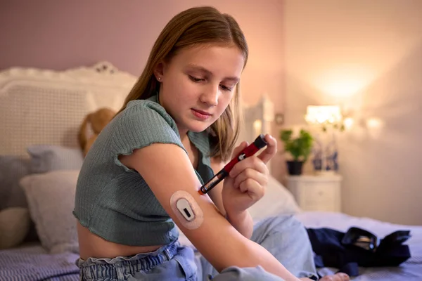 年轻的糖尿病女孩坐在床上在家用试剂盒测量和检查胰岛素水平 — 图库照片