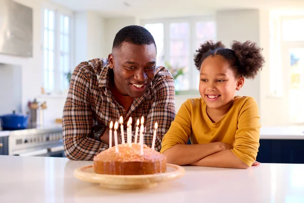 自家製の誕生日ケーキでキャンドルを吹いて祝うキッチンでお父さんと娘 — ストック写真