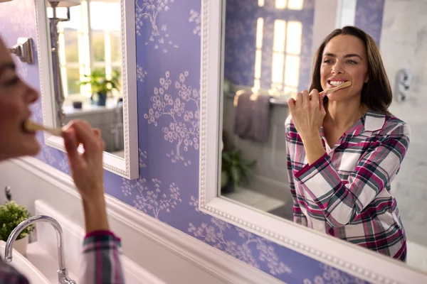 穿着睡衣在家的女人穿着浴室镜刷牙 — 图库照片