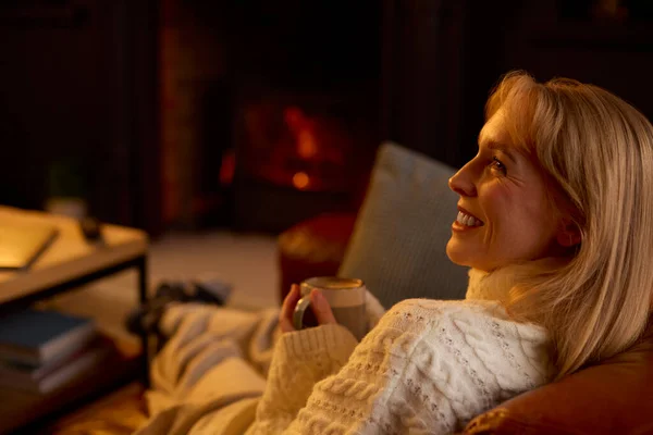 Vrouw Thuis Lounge Met Gezellig Vuur Met Warme Drank — Stockfoto