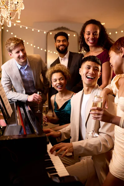 クリスマスや新年のパーティーでピアノの周りの友人のグループ一緒に祝う — ストック写真