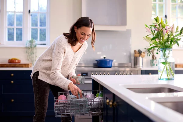 自宅のキッチンで食器洗い機をロードする女性 — ストック写真