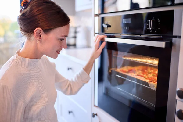Γυναίκα Στην Κουζίνα Στο Σπίτι Βλέποντας Σπιτική Πίτσα Στο Φούρνο — Φωτογραφία Αρχείου