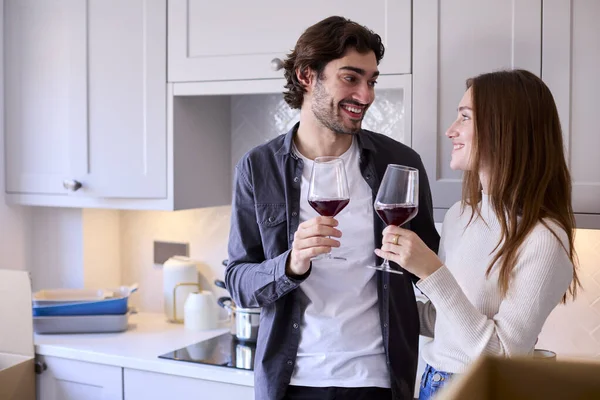 一緒にキッチンでワインのグラスで祝う自宅でロマンチックな若いカップル — ストック写真