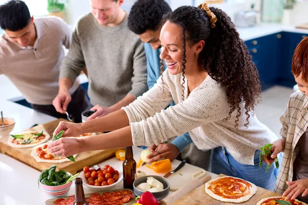 Groep Van Vrienden Thuis Keuken Toevoegen Toppings Aan Zelfgemaakte Pizza — Stockfoto