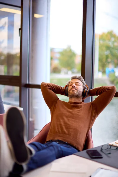 기사보기 인기있는 사업가 사무실에서 헤드폰으로 음악을 — 스톡 사진