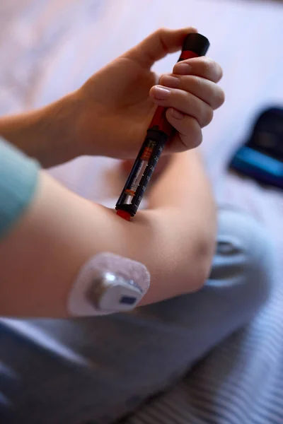 血糖値をチェックするために測定するためにインスリンペンを使用して自宅でベッドの上で糖尿病の女の子のクローズアップ — ストック写真