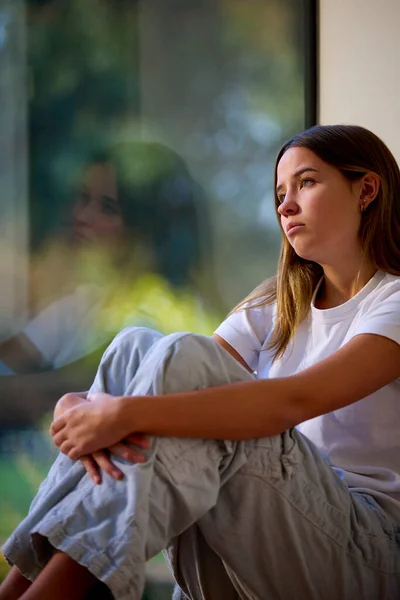 Przygnębiony Nastolatek Dziewczyna Siedzi Patrząc Przez Okno Domu — Zdjęcie stockowe