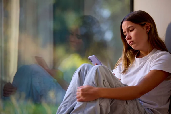Depressed Teenage Girl Sitting Window Home Looking Mobile Phone — Stock Photo, Image