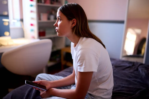 Καταθλιπτικό Έφηβο Κορίτσι Κάθεται Στο Κρεβάτι Στο Σπίτι Κοιτάζοντας Κινητό — Φωτογραφία Αρχείου