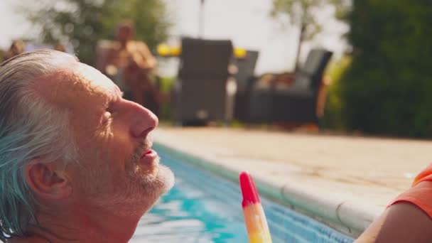 在家庭暑假期间 爷爷和孙子在游泳池边吃冰棍 动作缓慢 — 图库视频影像
