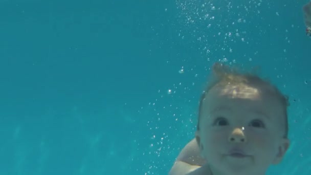 夏休みに家族と一緒にプールで水中で泳ぐ赤ちゃん スローモーションで撮影 — ストック動画